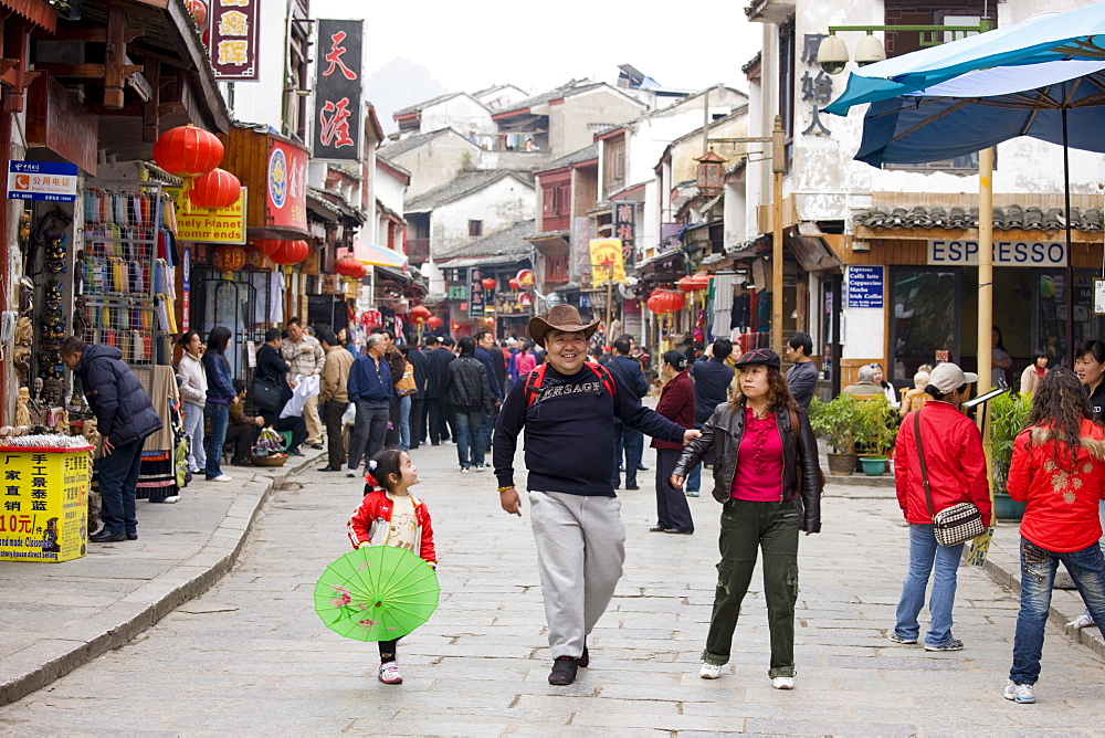 Tourist family in shopping street, Yangshuo. China has a one child policy to limit population.