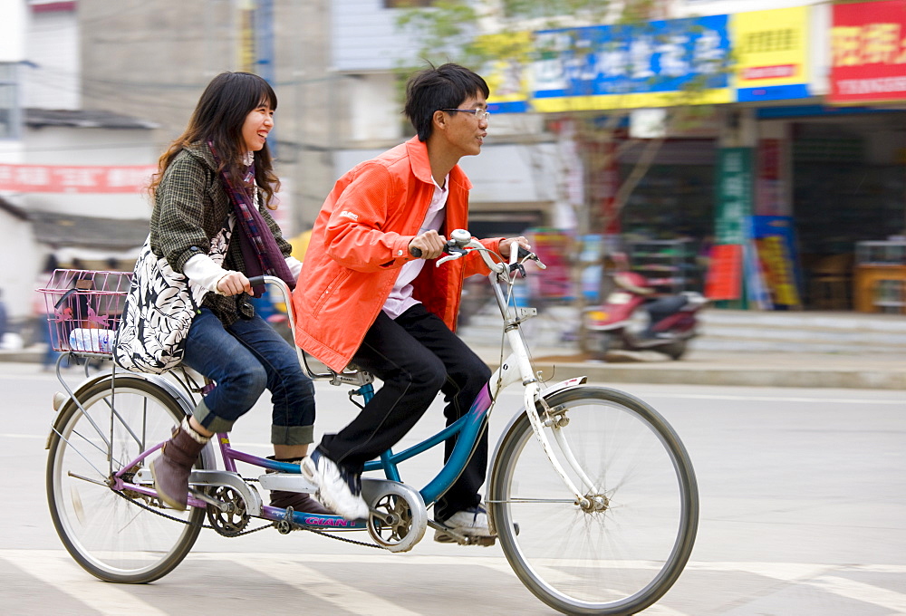 Couple on a tandem bicycle in Yangshuo street, China