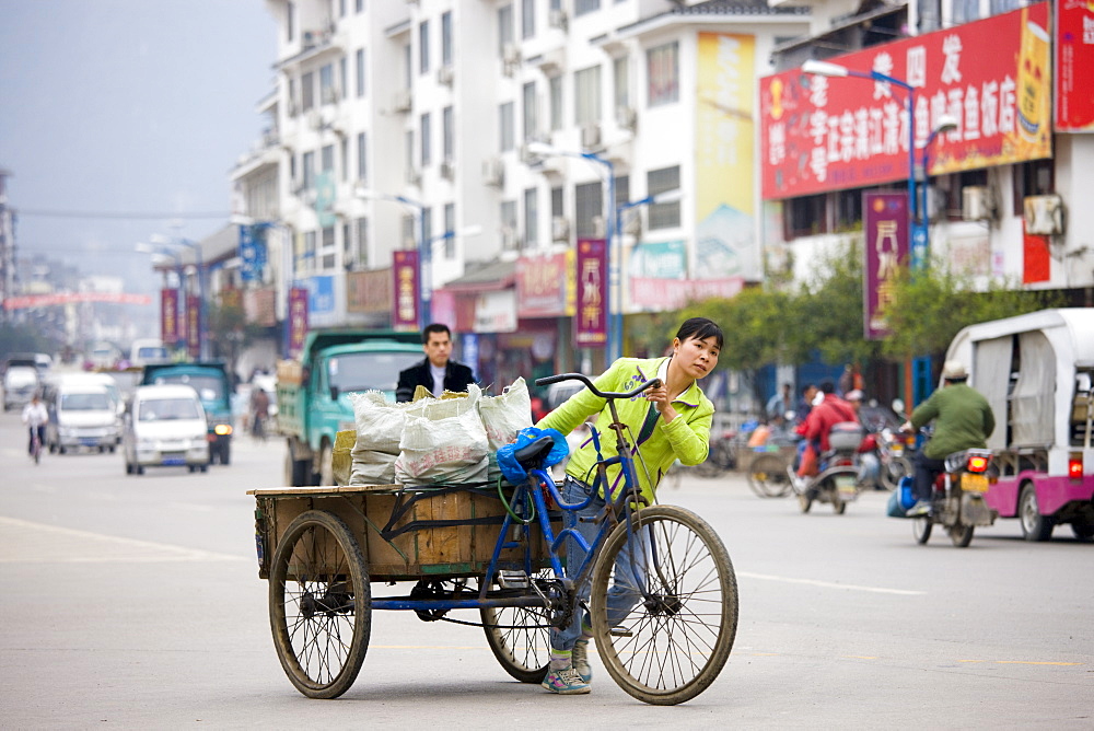 Woman with bicycle delivery cart in Yangshuo street, China