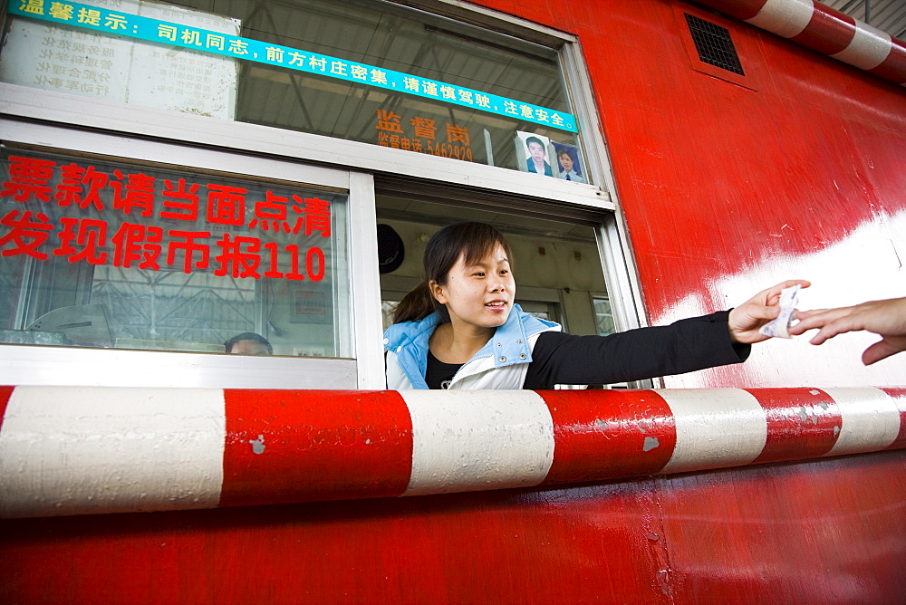 Woman in toll booth collecting payments, Guilin, China