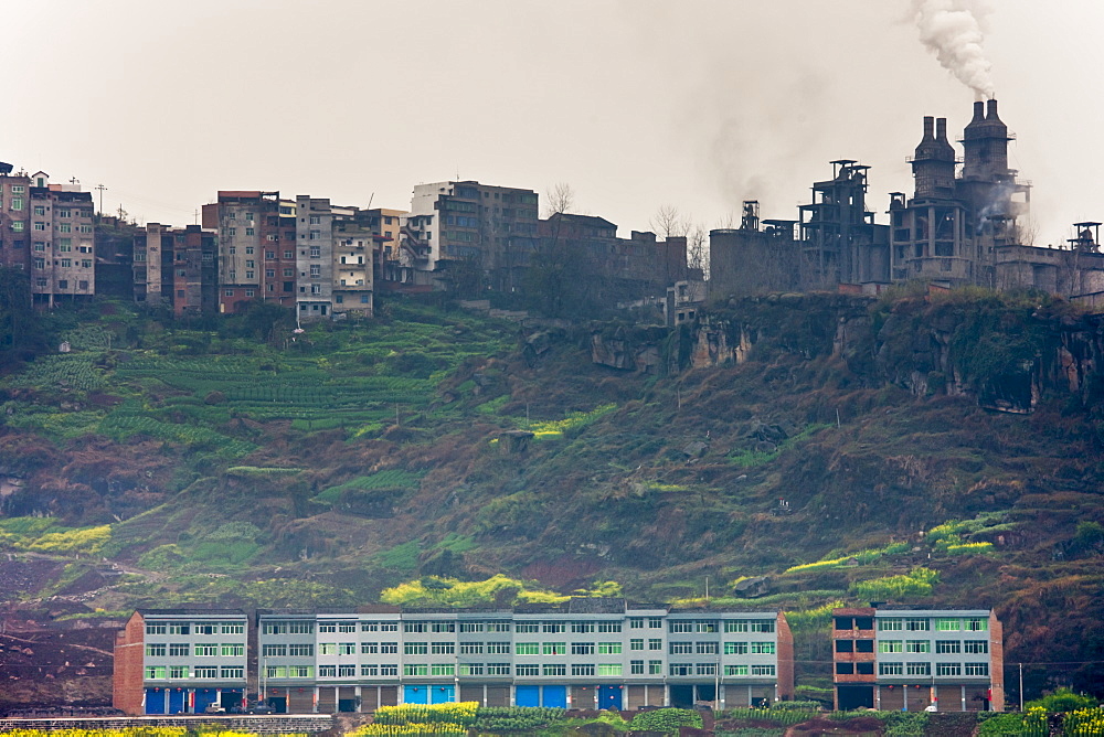 Houses in the shadow of a cement factory, beside the Yangtze River, China