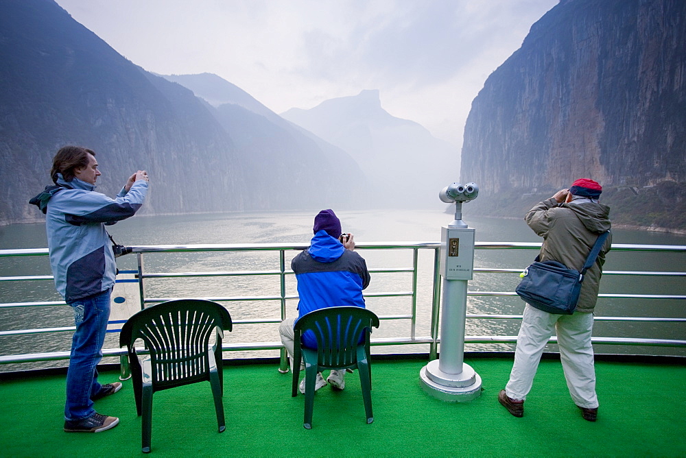 Tourists take photographs from the deck of a Victoria Line Cruise Ship, Yangze River, China