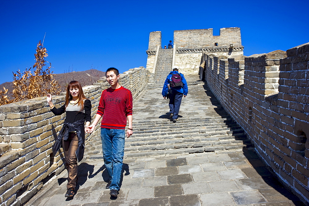 Tourist couple walk the ancient Great Wall of China at Mutianyu, north of Beijing, China