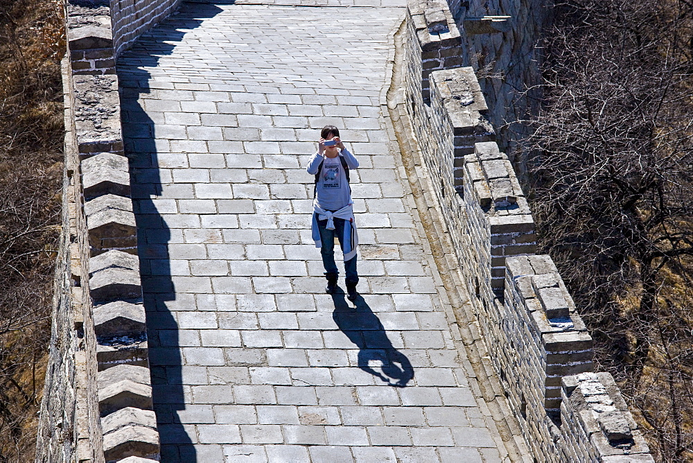 Tourist takes a photograph on the ancient Great Wall of China at Mutianyu, north of Beijing (formerly Peking), China