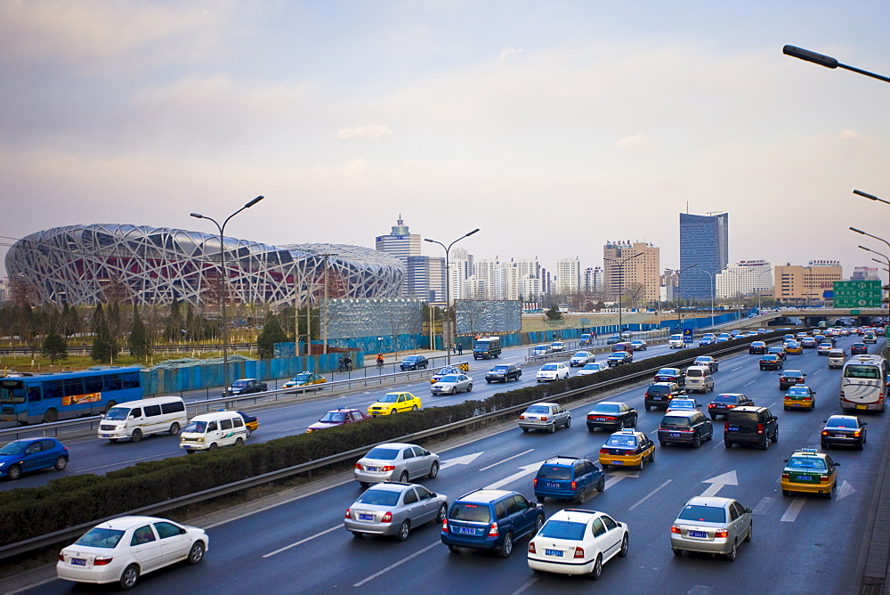 Traffic on motorway passes Olympics site of The Beijing National Stadium (Bird's Nest), China