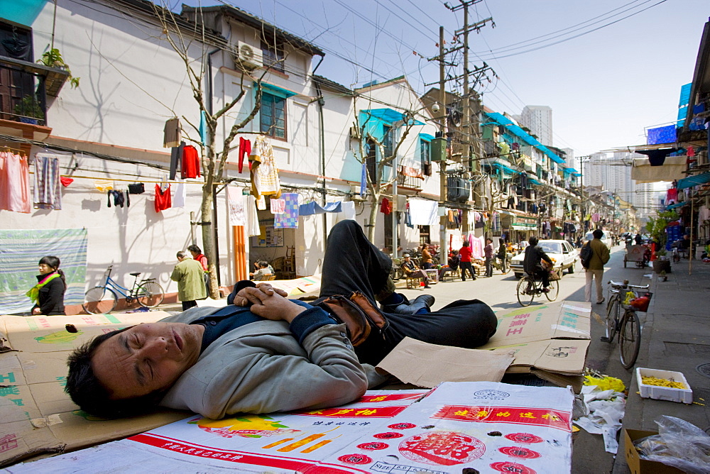 Man sleeps on cardboard in Zi Zhong Road, old Shanghai, China