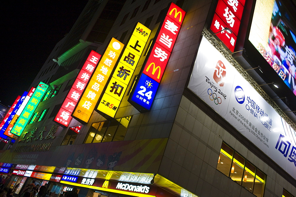 McDonalds fastfood restaurant with advertising alongside Chinese companies on Wangfujing Street, Beijing, China