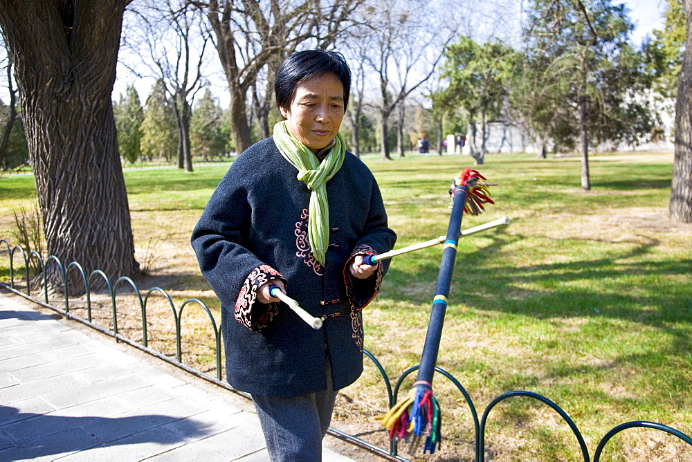 Woman practises tai chi with sticks in park of the Temple of Heaven, Beijing, China