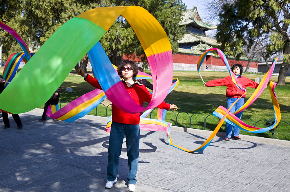 Women practise tai chi dancing with ribbons in park of the Temple of Heaven, Beijing, China