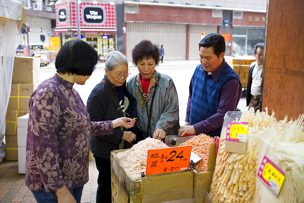 Women shopping for Chinese dried fish and medicines in shop in Wing Lok Street, Sheung Wan, Hong Kong, China