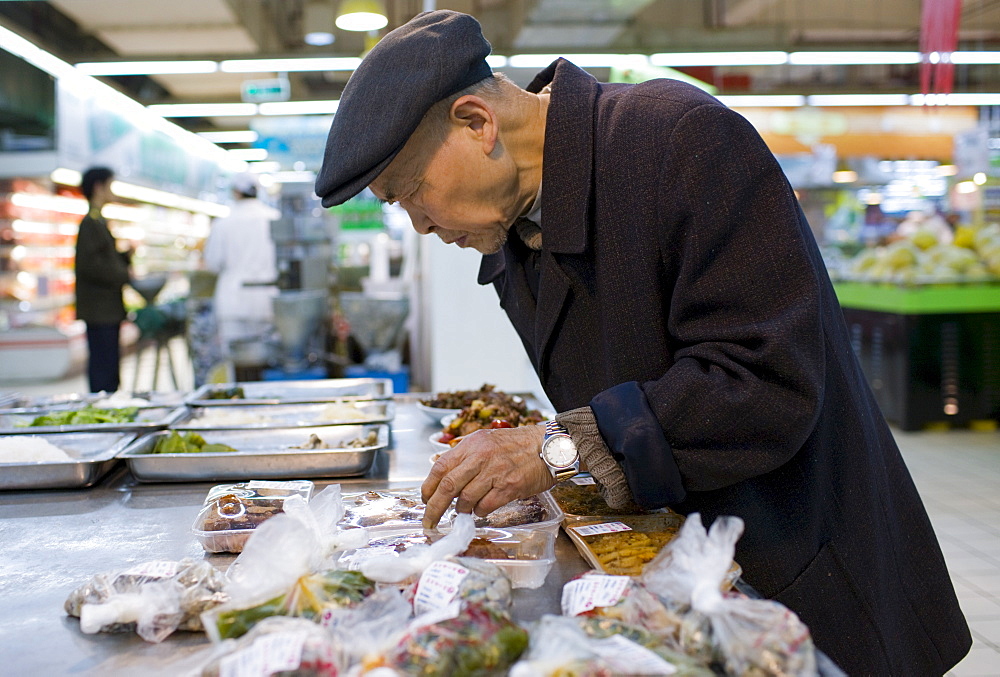 Man choosing shrink wrapped food in supermarket, Chongqing, China