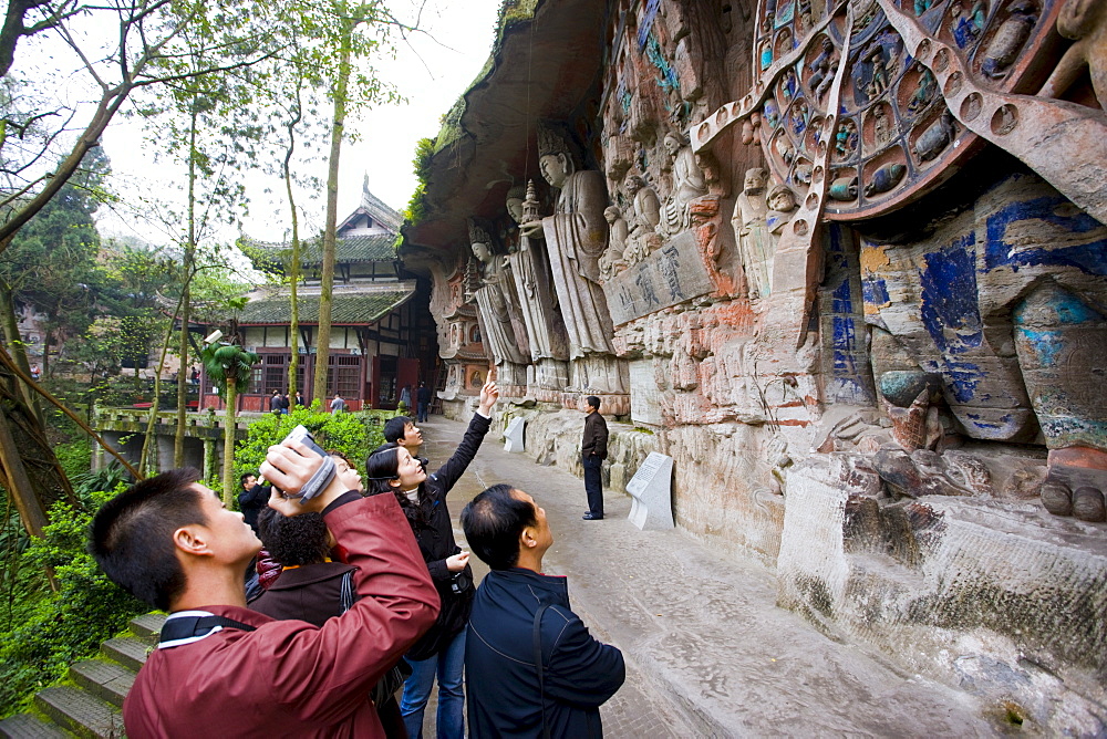 Tourist photographs Anicca, God of Destiny holds wheel of life, Dazu rock carvings, Mount Baoding, China