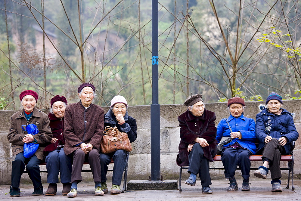 Elderly Chinese women sit together on benches in Chongqing, China