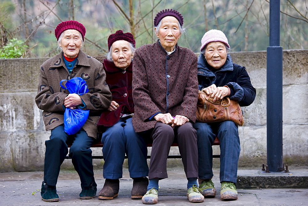 Elderly Chinese women sit together on a bench in Chongqing, China