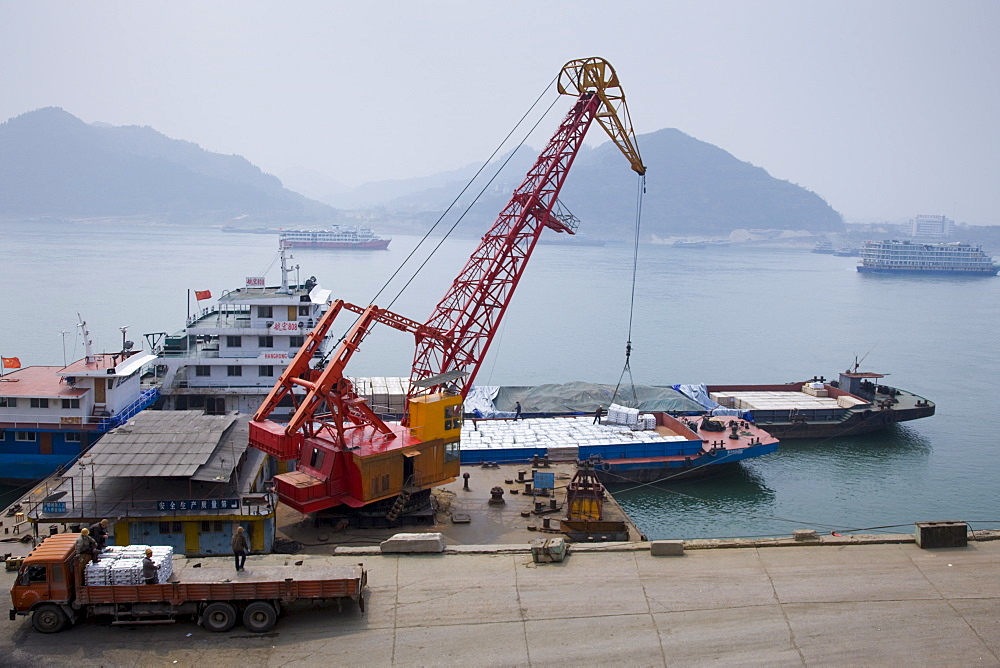 Loading dock crane lifts aluminim ingot blocks onto cargo ship, Yichang, China