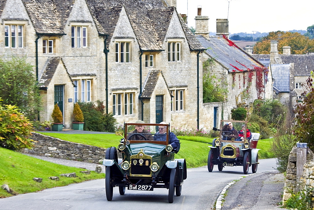 Vintage cars drive through Windrush village on a Veteran Car Club rally day, Gloucestershire, United Kingdom