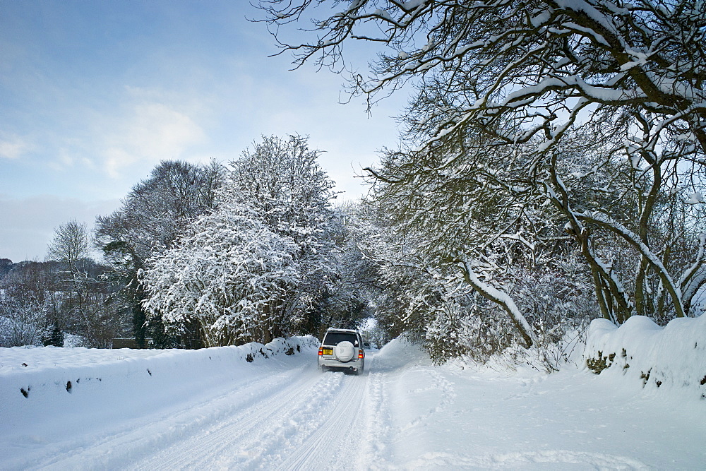 Four wheel drive vehicle in snow-covered lane in Swinbrook, The Cotswolds, UK