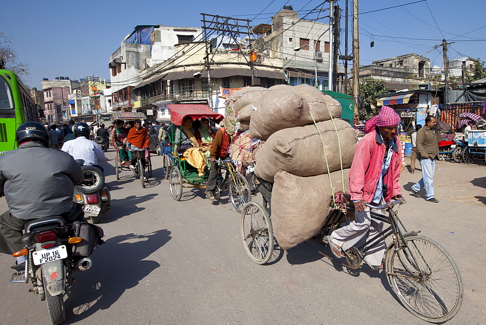 Street scene at Daryagang as porter carries produce by bicycle in Old Delhi, India