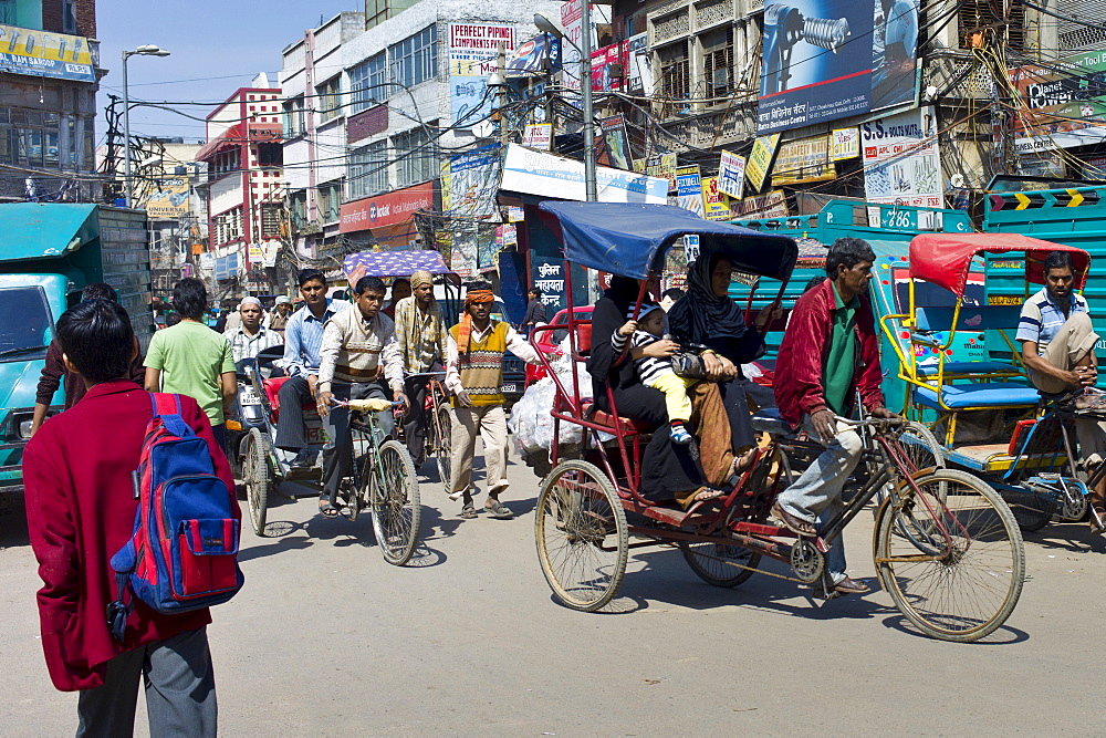 Schoolboy in school uniform heads to school along crowded street at Chawri Bazar in Old Delhi, India