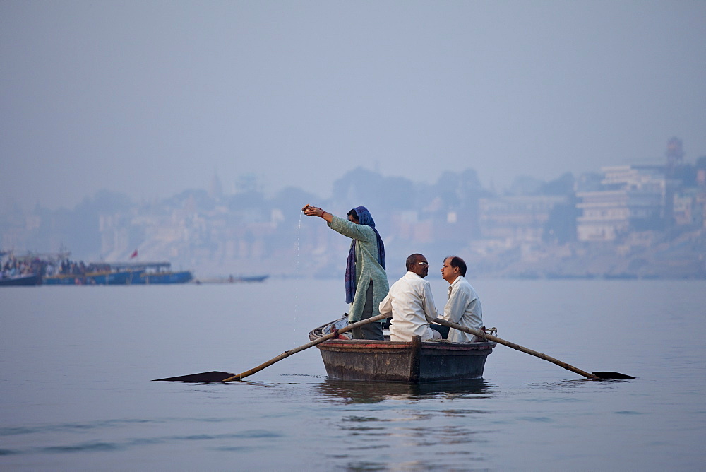 Traditional scene on River Ganges Hindu pilgrim pours Ganges water while praying at Varanasi, Benares, Northern India