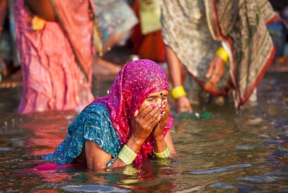 Indian Hindu pilgrim woman bathing in The Ganges River at Dashashwamedh Ghat in Holy City of Varanasi, Benares, India