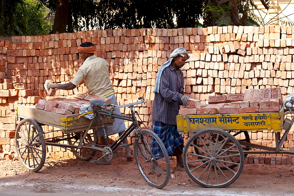 Indian men stacking TATA bricks in the city of Varanasi, Benares, Northern India