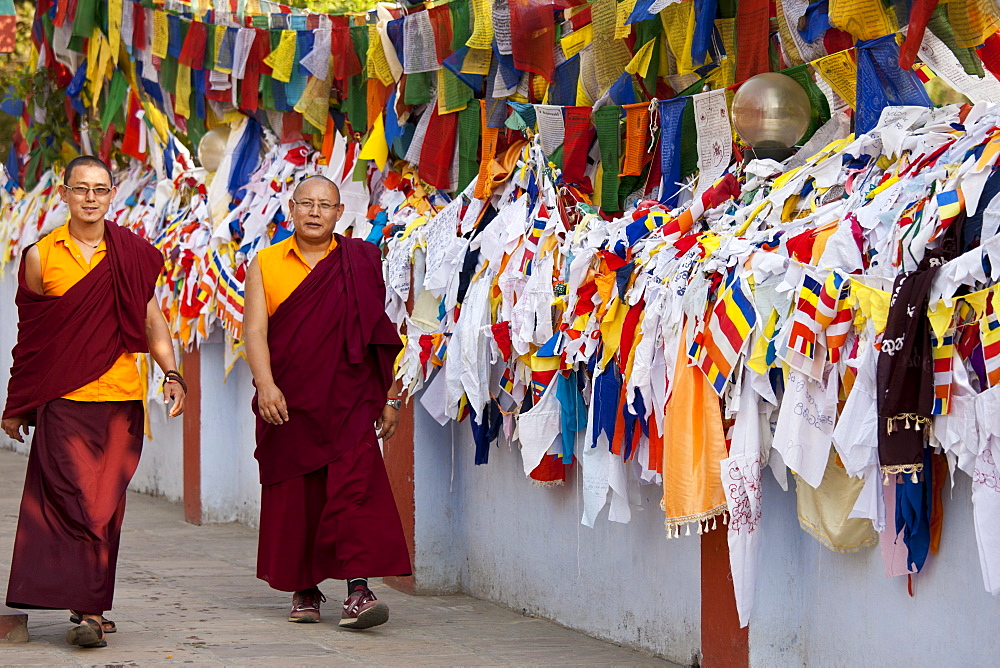 Buddhist monks pass prayer flags at Mulagandhakuti Vihara Temple at Sarnath near Varanasi, Benares, Northern India