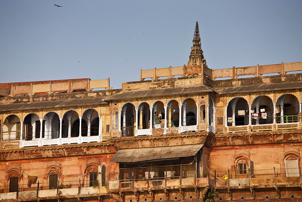 Man holding child in ancient building fronting the famous Ghats by The Ganges River in Holy City of Varanasi, India