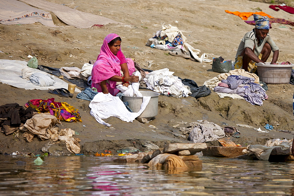 Indian man and woman doing laundry in the waters of The Ganges River at Cabua Pandey Ghat in City of Varanasi, Benares, India