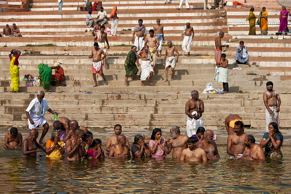 Indian Hindu men and women bathing and praying in the River Ganges by Kshameshwar Ghat in holy city of Varanasi, India