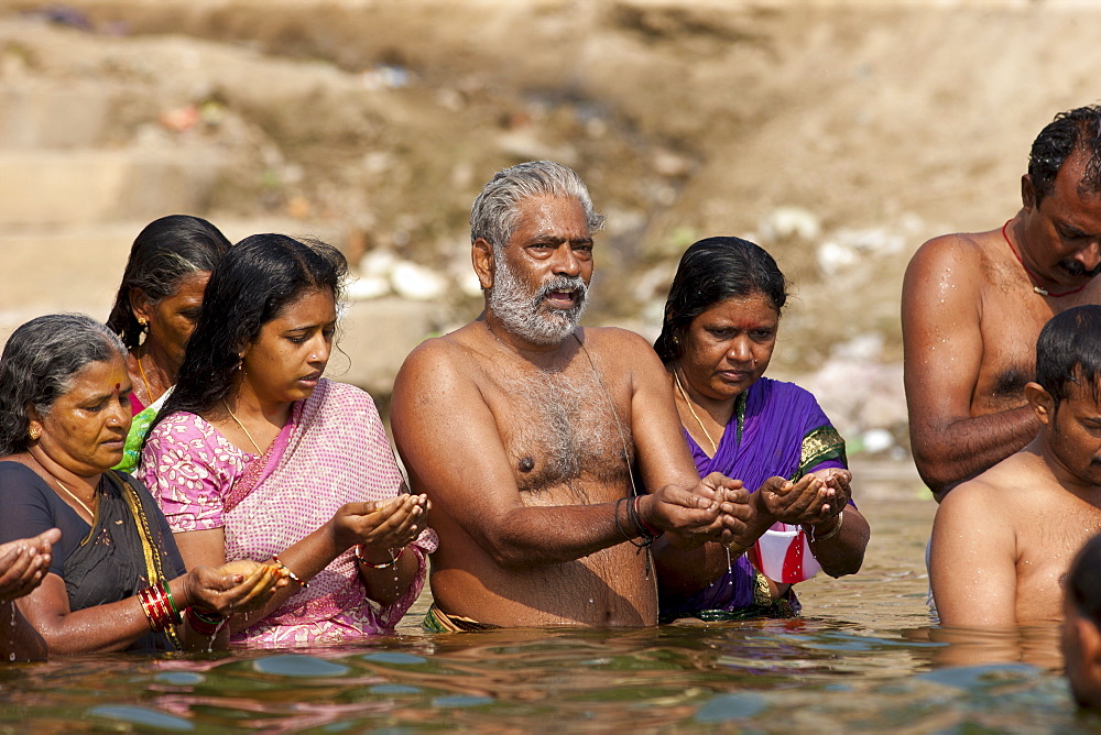 Indian Hindu men and women bathing and praying in the River Ganges by Kshameshwar Ghat in holy city of Varanasi, India