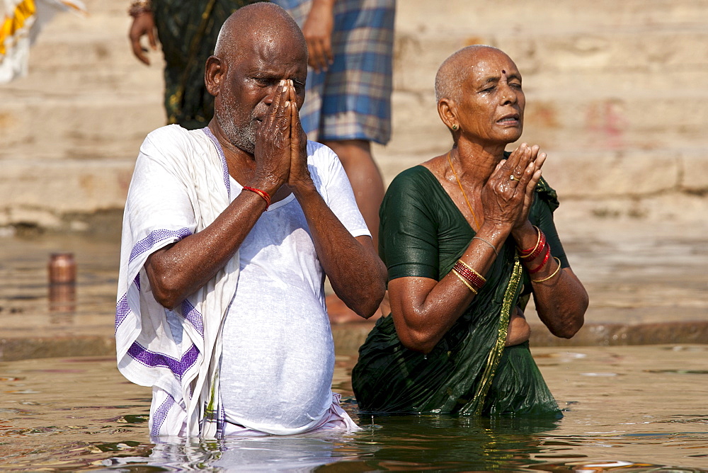 Indian Hindu couple bathing and praying in the River Ganges by Kshameshwar Ghat in holy city of Varanasi, India