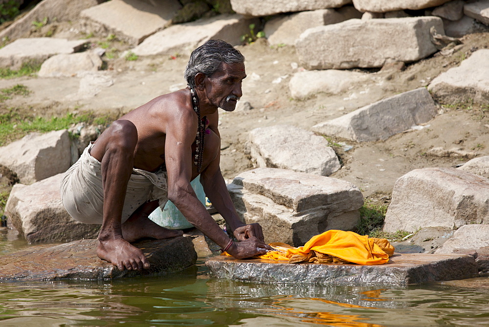 Indian doing laundry using traditional methods and the waters of The Ganges River at Kali Ghat in City of Varanasi, Benares, India