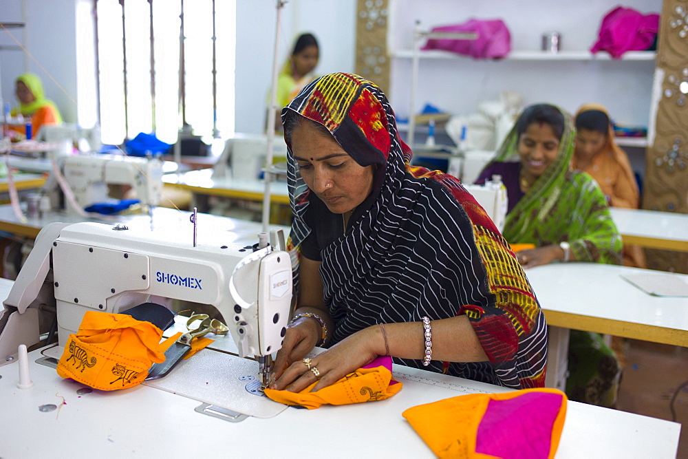 Indian woman sewing textiles at Dastkar women's craft co-operative, the Ranthambore Artisan Project, in Rajasthan, Northern India