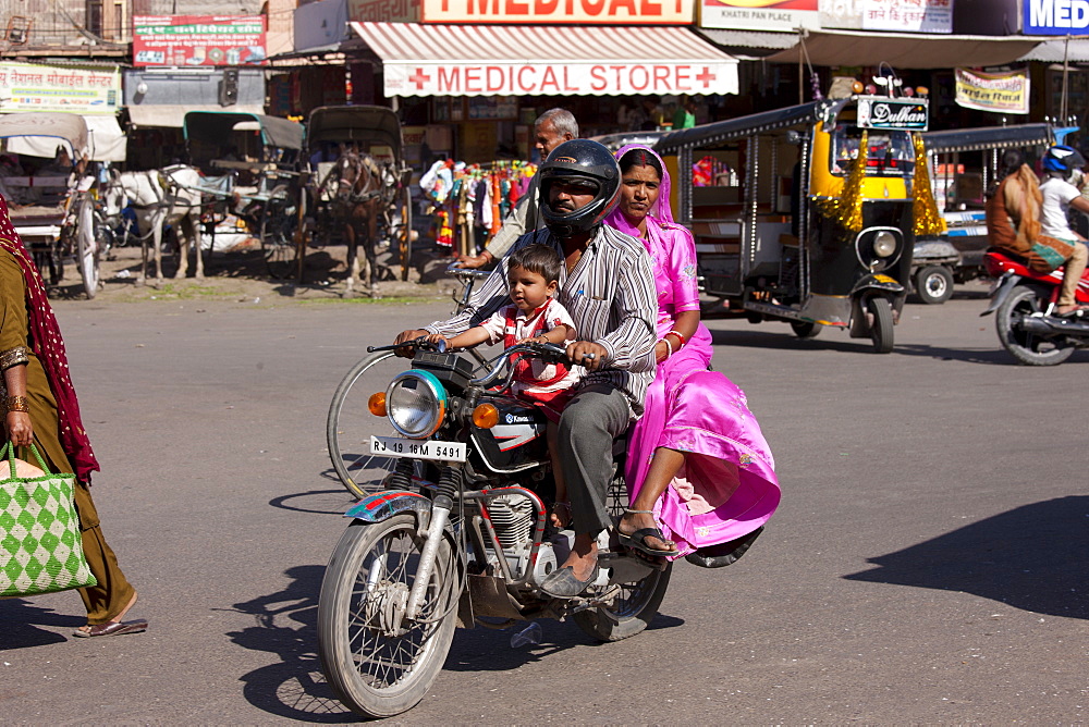 Indian family riding motorcycle, street scene at Sardar Market at Girdikot, Jodhpur, Rajasthan, Northern India