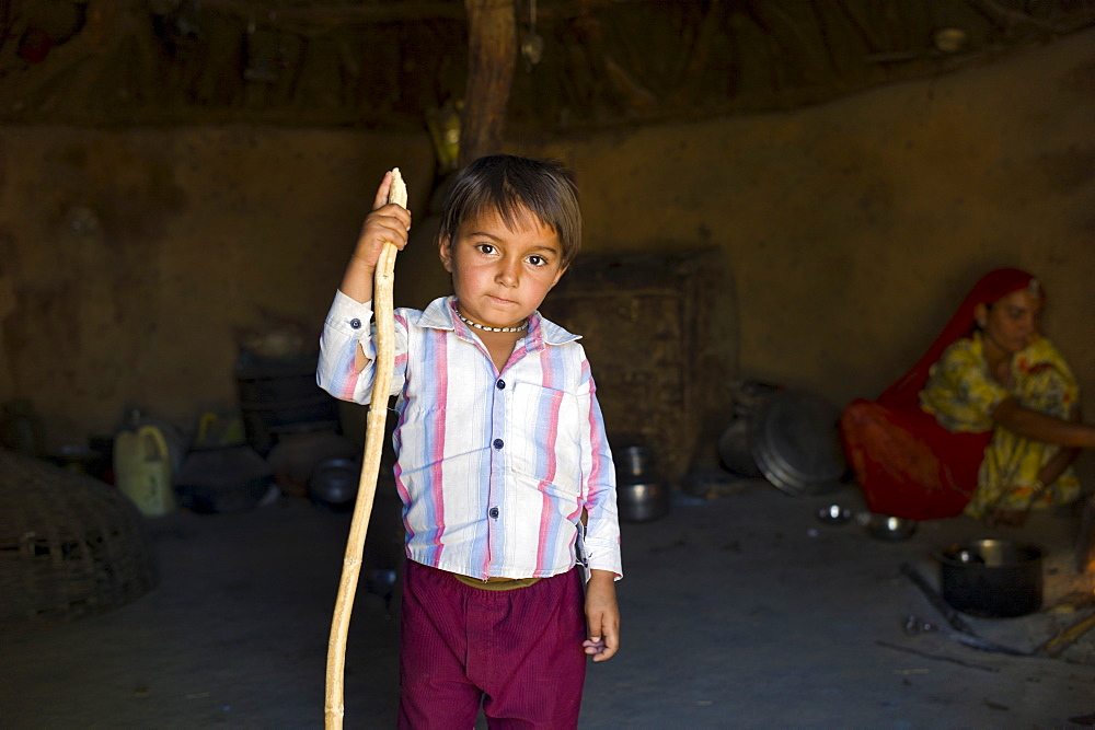 Indian boy inside his home made of mud bricks coated in cow dung in Bishnoi tribe village near Rohet in Rajasthan, Northern India