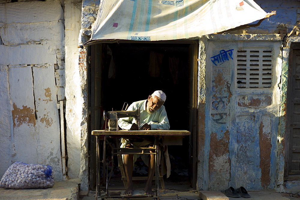 Indian man and wife sewing fabric in village of Rohet in Rajasthan, Northern India