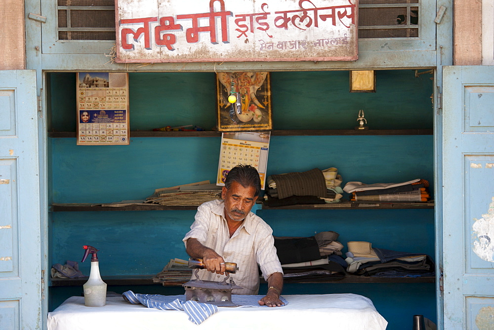 Indian man pressing clothes in his workroom in Narlai village in Rajasthan, Northern India