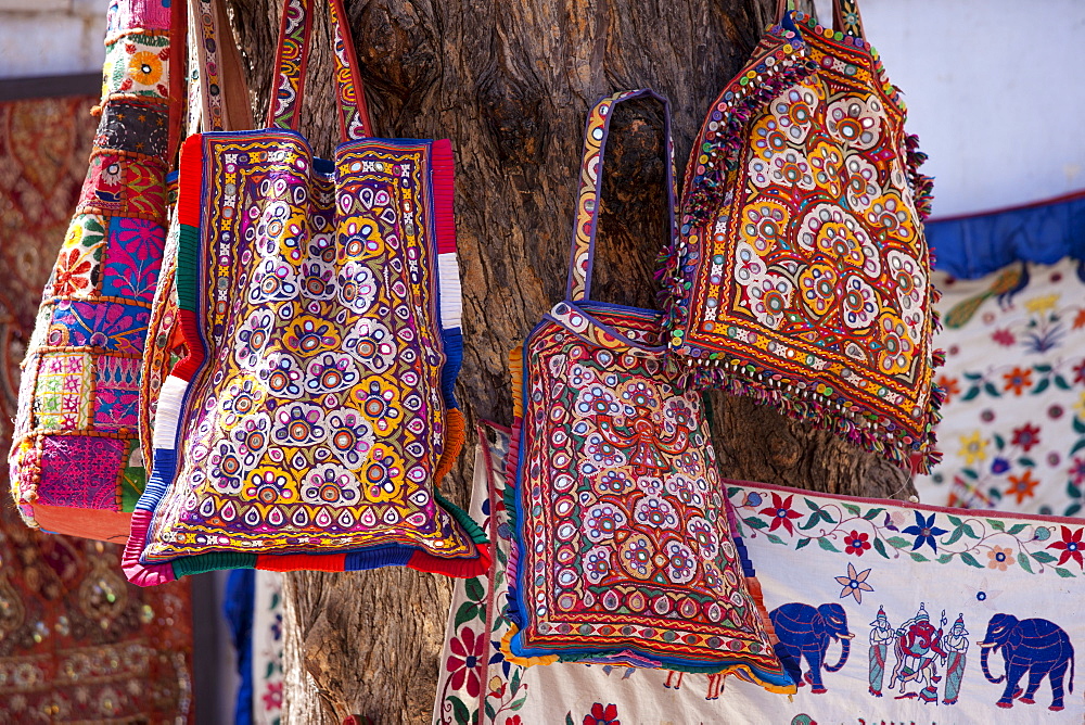 Decorated handbags on sale hanging from tree in street market in City Palace Road, Udaipur, Rajasthan, Western India