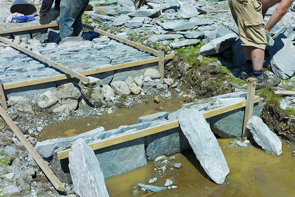 Workers pitching a path using Elterwater green slate, near Easedale Tarn in the Lake District National Park, Cumbria, UK