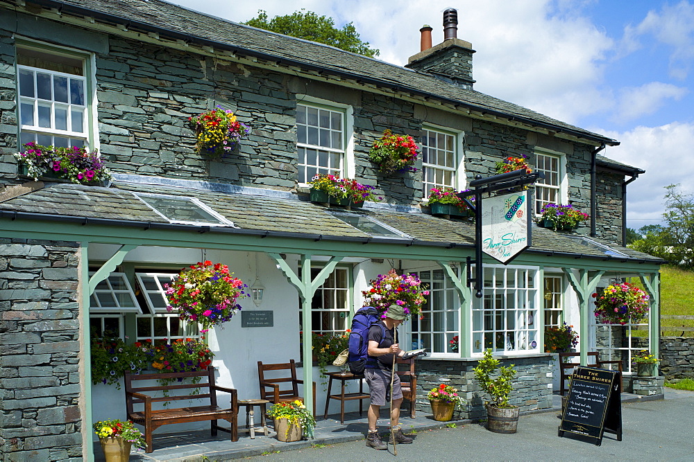 Walker at Three Shires Inn public house at meeting point of Cumberland, Lancashire and Westmoreland at Langdale in Lake District National Park, Cumbria, UK