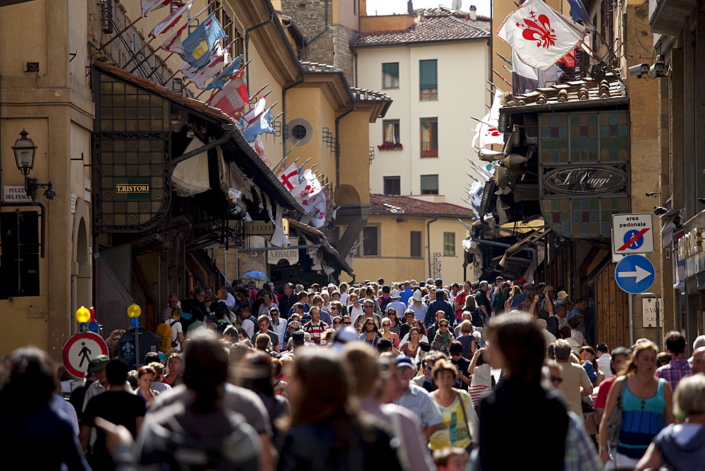 Crowds cross the Ponte Vecchio from the north side of the River Arno, Florence, Tuscany, Italy