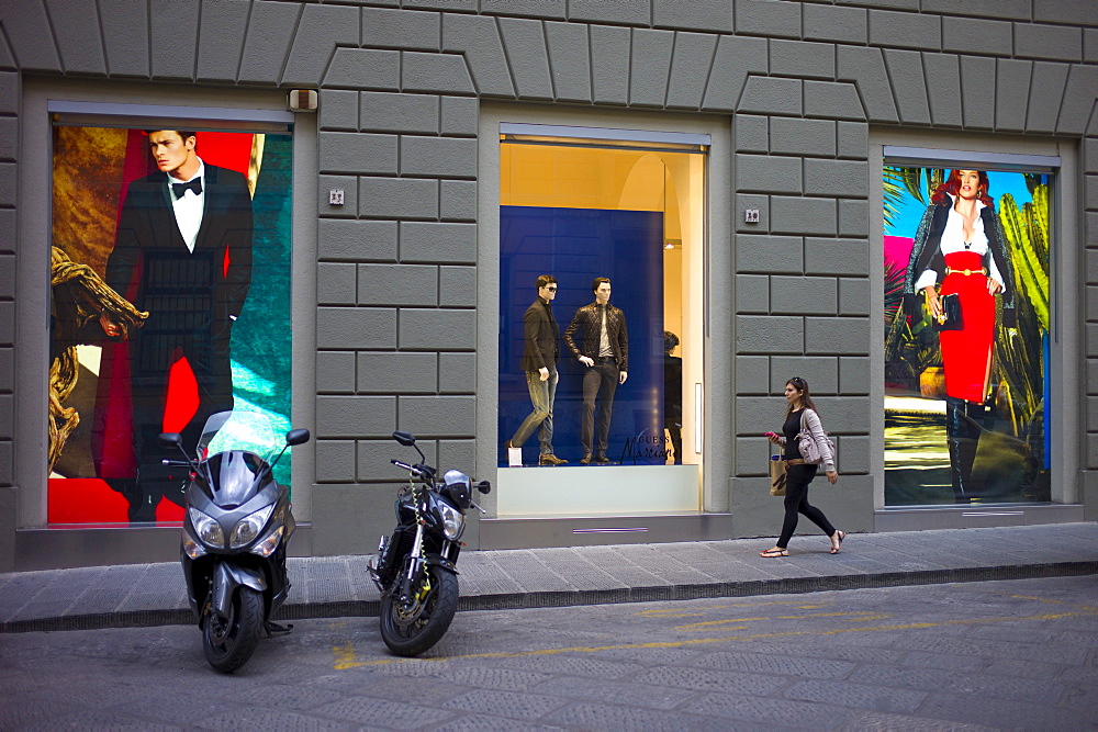 Stylish Italian woman walks past fashion displays of Guess Marciano casuals in Via de Pecori in Florence,Tuscany, Italy