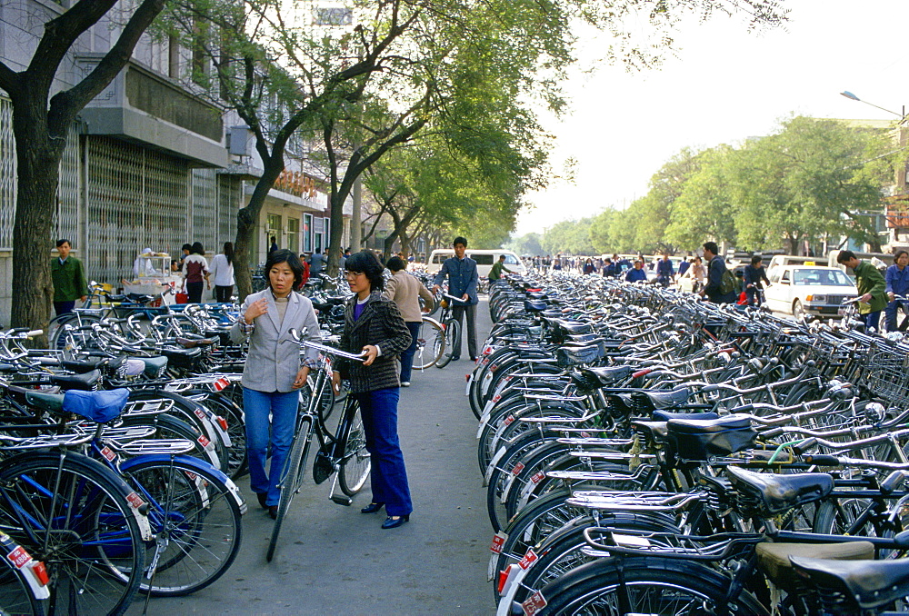 Young women parking bicycle in crowded bicycle park, Beijing, China