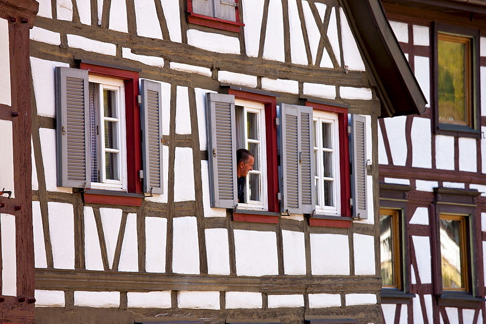 Man at window of traditional quaint timber-framed house in Schiltach in the Bavarian Alps, Germany