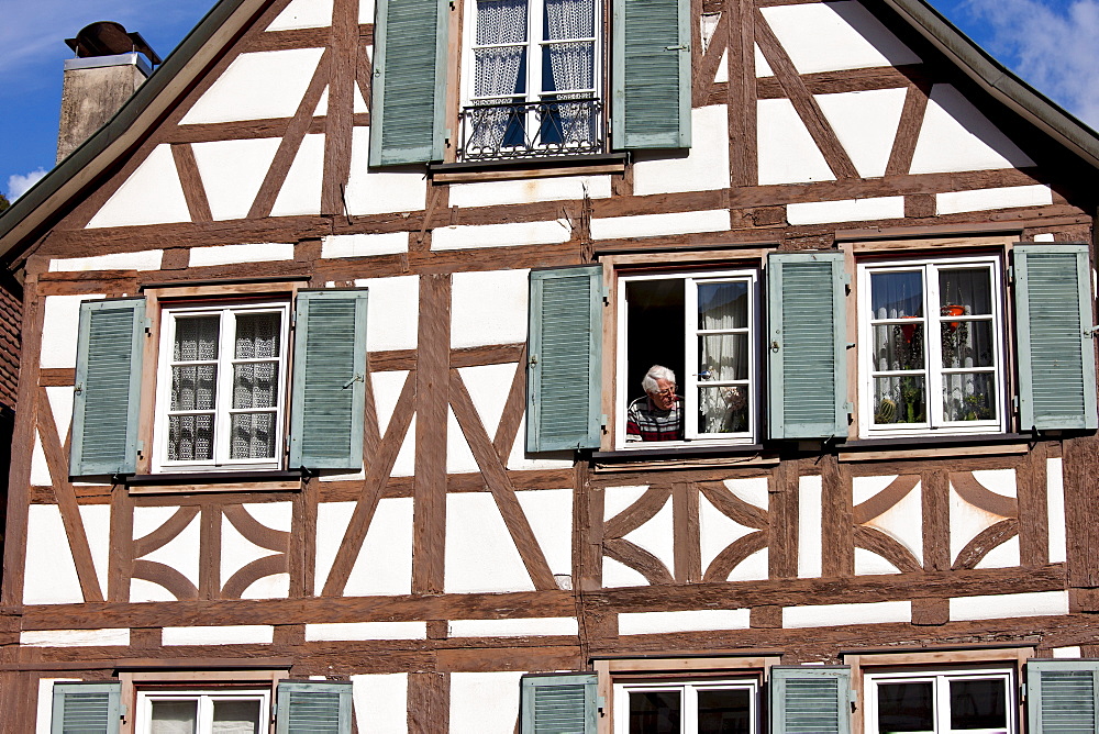 Man at window of traditional quaint timber-framed house in Schiltach in the Bavarian Alps, Germany