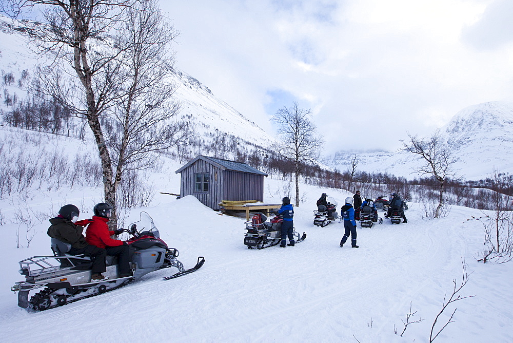 Pitstop for snowmobiling group among arctic alps in the Arctic Circle near Holt in the region of Tromso, Northern Norway