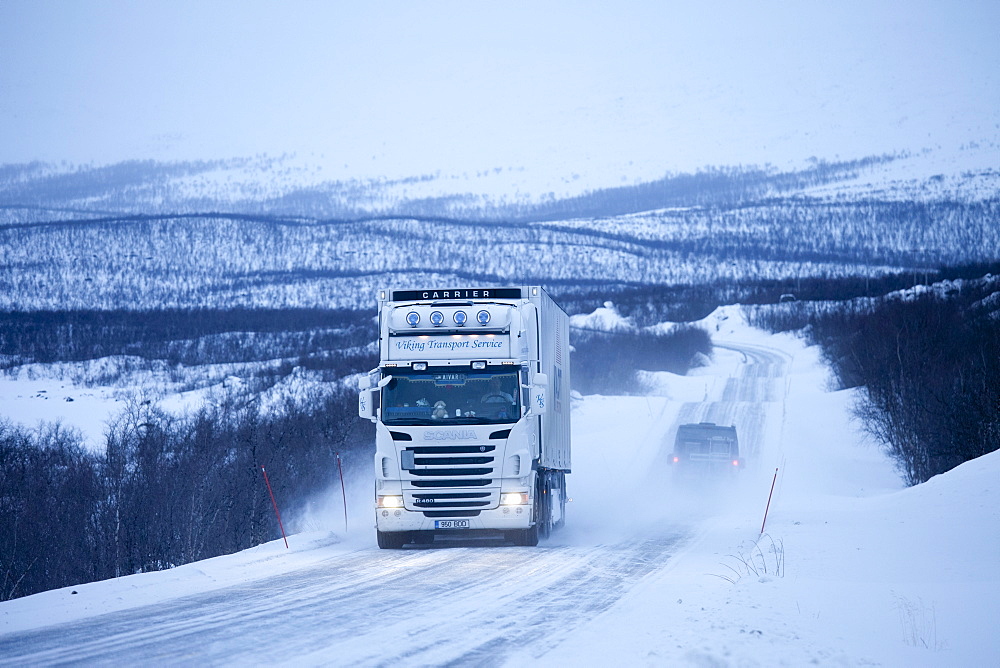 Viking Transport Service truck travels through arctic wilderness at nightfall by Kilpisjarvi on route from Norway into Finland