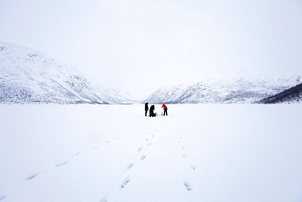 Ice fishing on frozen lake in the arctic alps in the Arctic Circle on Ringvassoya Island in the region of Tromso, Northern Norway