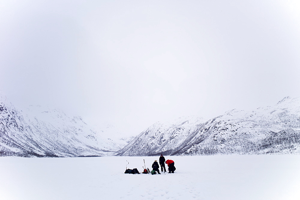 Ice fishing on frozen lake in the arctic alps in the Arctic Circle on Ringvassoya Island in the region of Tromso, Northern Norway